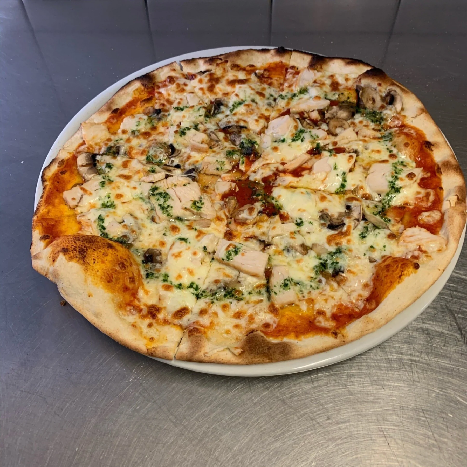 Pizza dorée à la croûte charbonnée, sortie du four